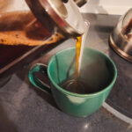 Fresh coffee being poured from a French press into a cup