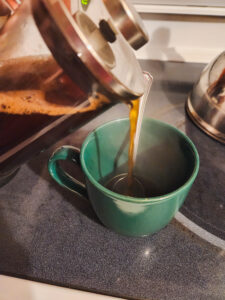 Fresh coffee being poured from a French press into a cup
